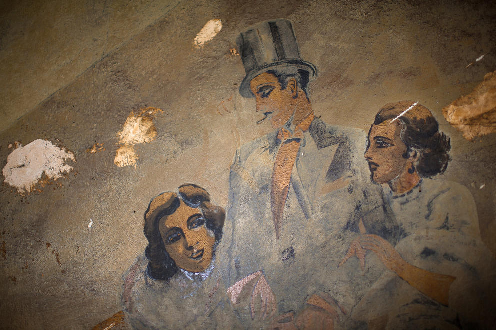 Two women flank a man in a top hat in one of the 1920s murals that line a staircase inside the Louisa Hotel in Seattle's Chinatown International District.