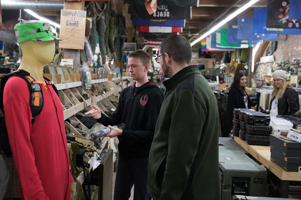 Sylvia Etter (center) and Ryan Denson (right) peruse clothing items inside the Federal Army & Navy Surplus store in Seattle.
