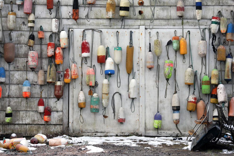 A collection of buoys are seen hanging from a garage near Astoria. 