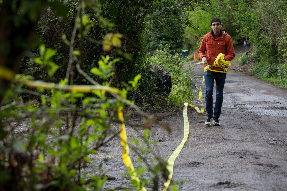 Protester Ranjan Pradeep of Seattle DSA removes caution tape placed by SPD during a sweep of Ravenna Woods homeless encampment near Seattle's University Village neighborhood, Tuesday, April 17.