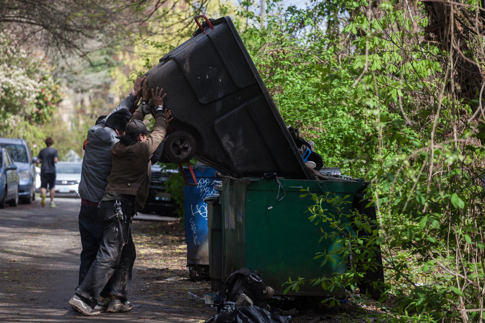 Protesters help a resident throw away trash during a sweep of Ravenna Woods homeless encampment near Seattle's University Village neighborhood, Tuesday, April 17.