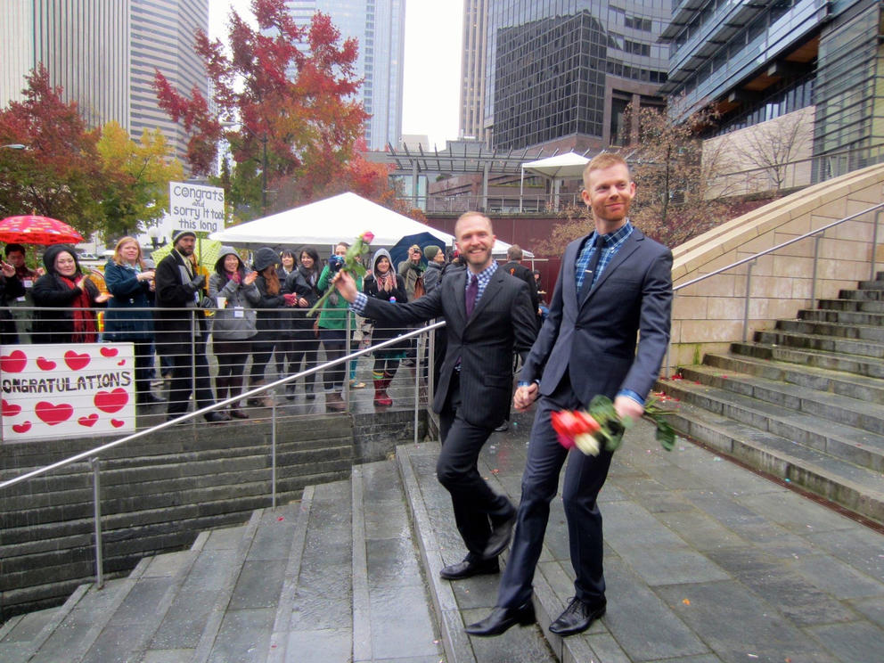 Ryan Hicks and Jeff Dorion walk down stairs outside of City Hall, celebrators line the walk way in the background, some holding signs