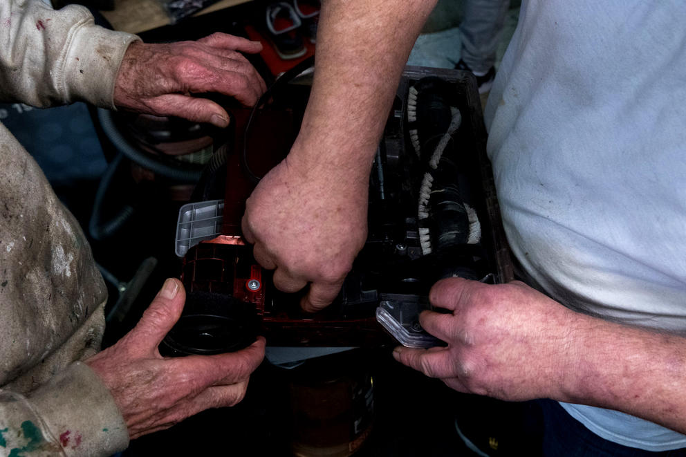 Hands of longtime customer Mark De Benedetti and co-owner Guy McNally work on a vacuum at The Vac Shop in Seattle's Georgetown neighborhood, Nov. 16, 2018.
