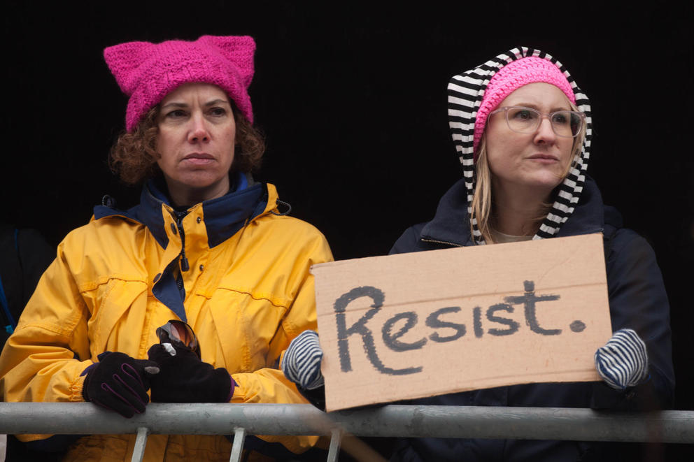 Women standing atop a parking structure at Seattle Central Community College hold a sign that says "resist," as they watch the Seattle Women’s March 2.0 in Seattle, Jan. 20, 2018.