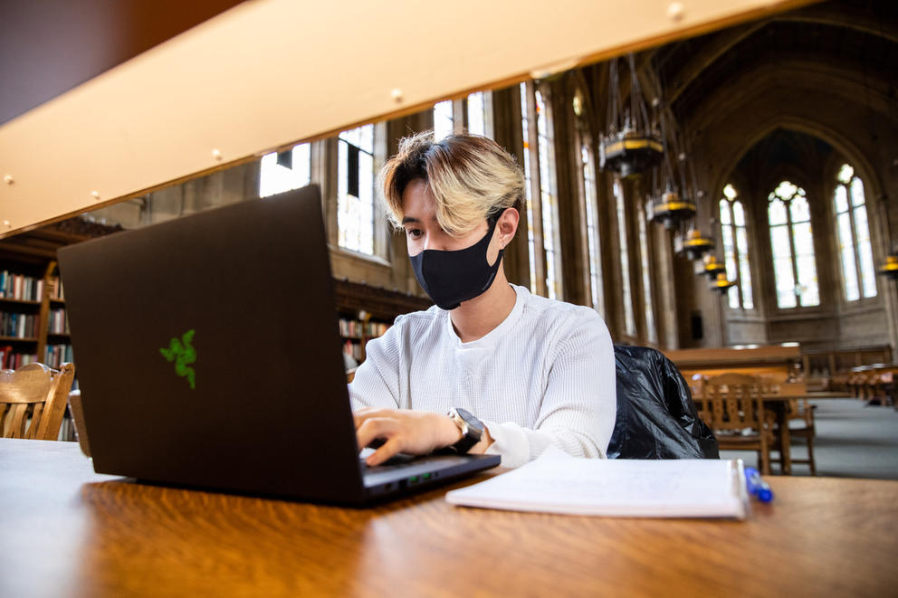 Zulkifli Sales wears a face mask and types on his laptop
