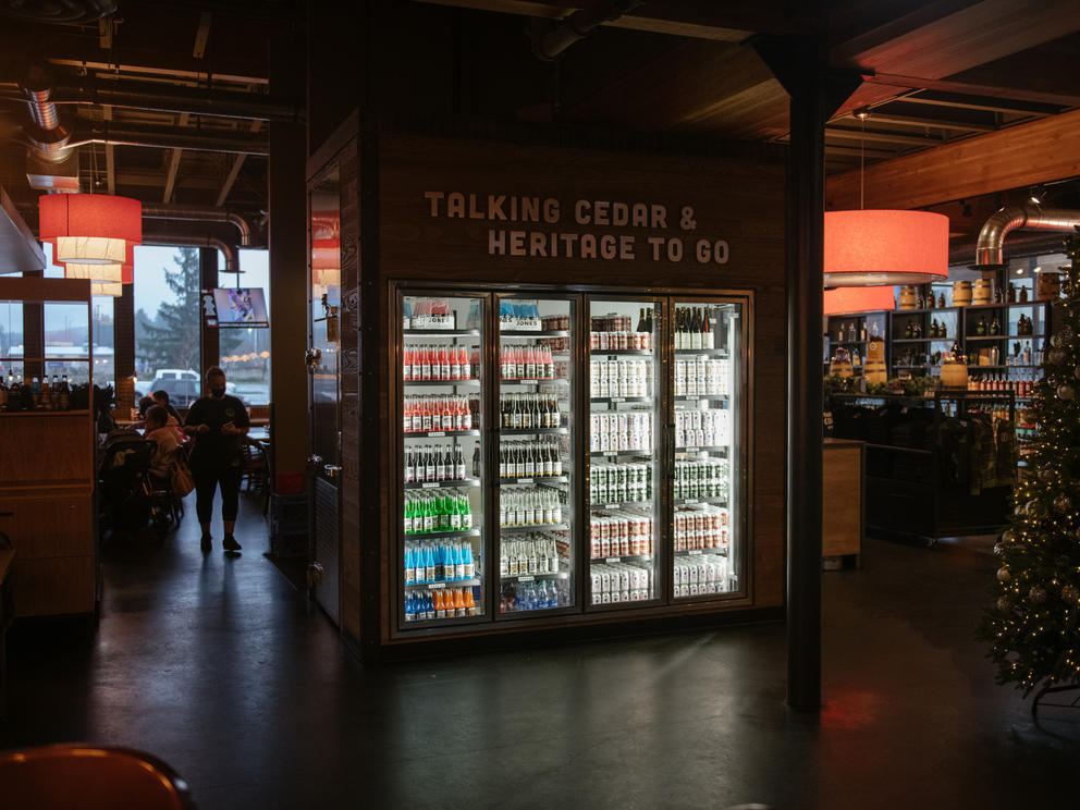 An illuminated drink refrigerator is full of beverages in a darkened bar 