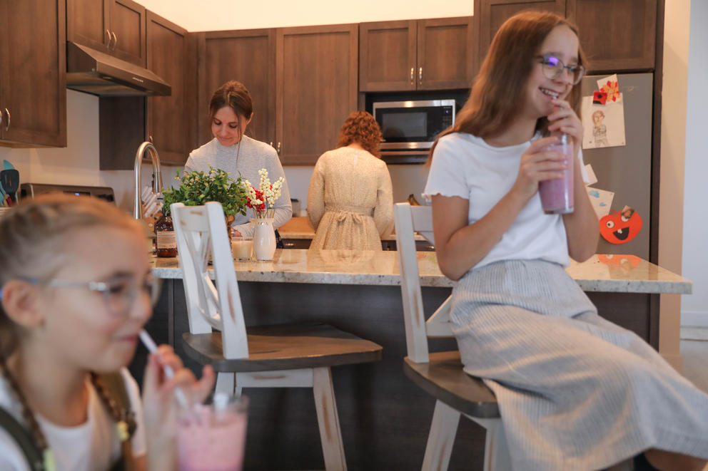 Yeva, 9, and Sofiia, 12, drink smoothies as their mother Karyna and older sister Mia, 15, clean up in the kitchen