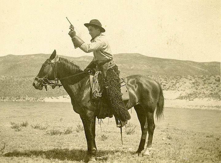 Cowboy mounted on a horse with treeless hills in the background