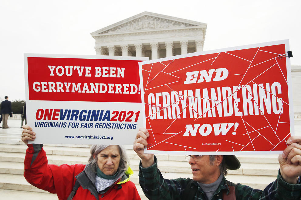 Protesters hold signs saying "End Gerrymandering now!" and "You've been gerrymandered!"