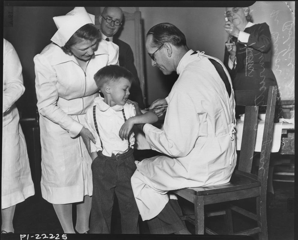 A doctor gives an immunization shot to a child.