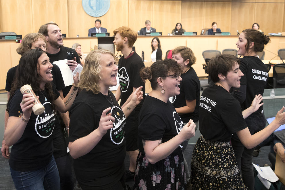 Activists sing during a City Hall meeting