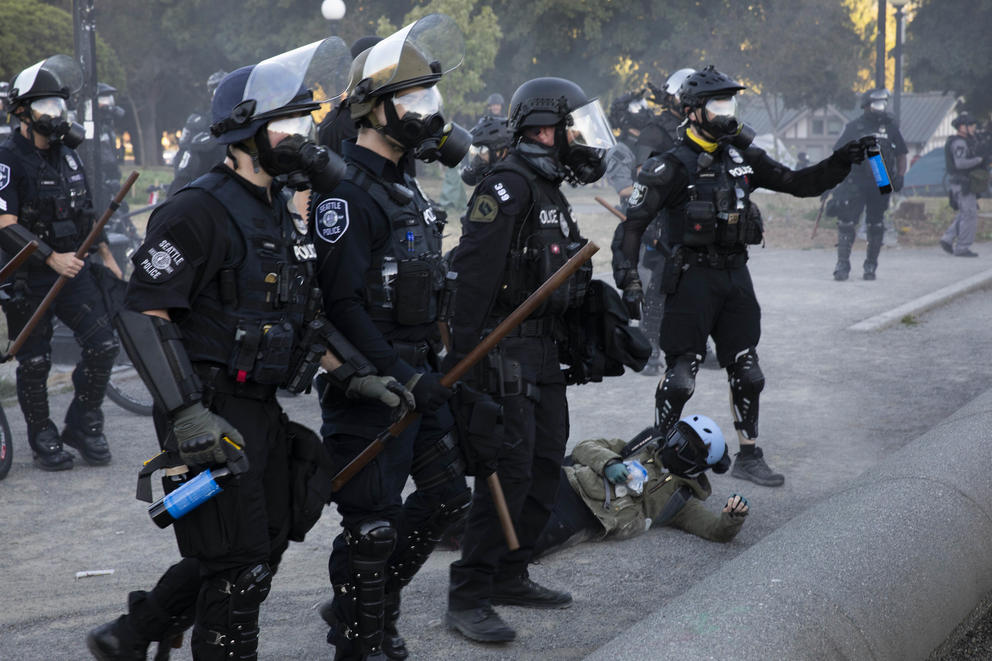 Four Seattle police officers wearing gas masks on a street