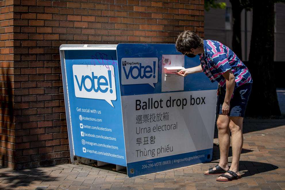A voter puts a ballot in a ballot drop box