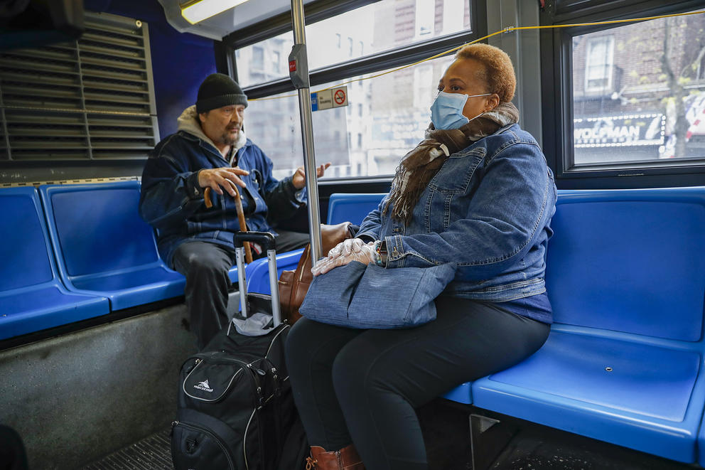 A man without a mask and a woman with a mask, on a bus