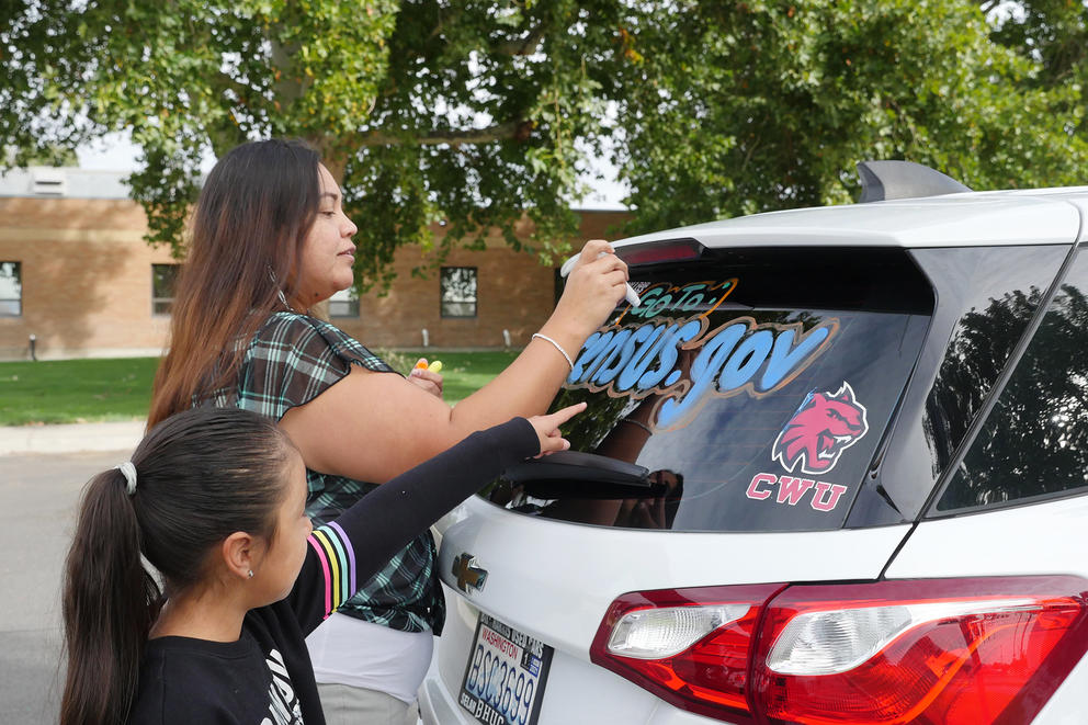 A woman and girl decorate a car with the words 2020 census