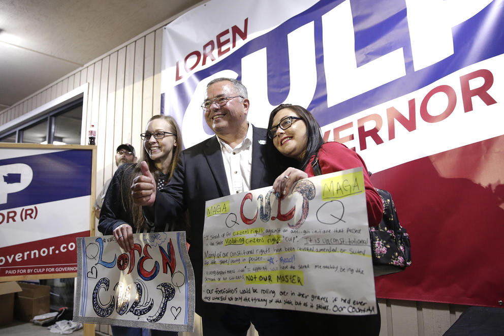 Loren Culp poses with two people holding signs that read 'Culp' and 'Q'