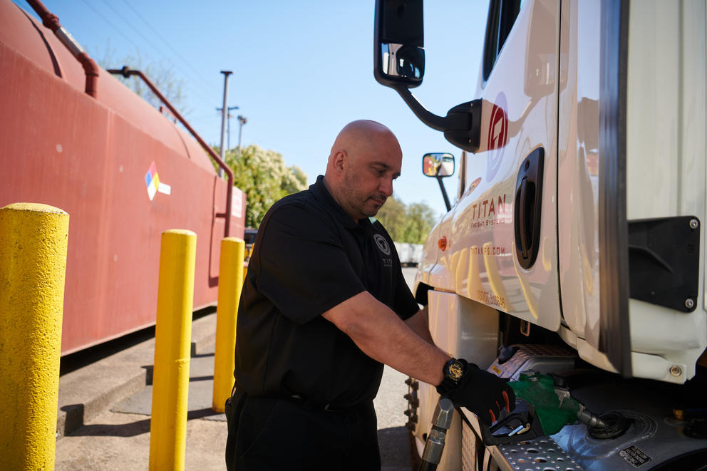 A man filling a commercial truck's gas tank