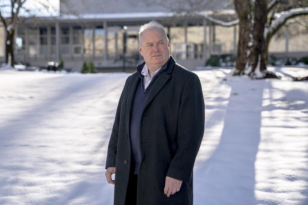 Jim Walsh stands in front of a Washington state Capitol office building with snow and tree behind him