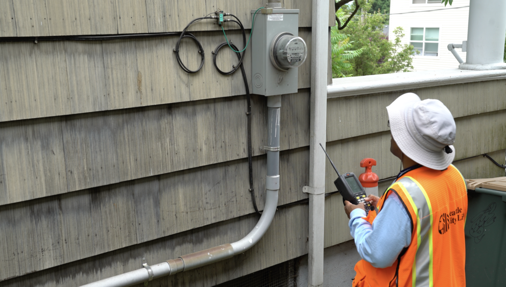 A Seattle City Light employee reads a traditional meter.