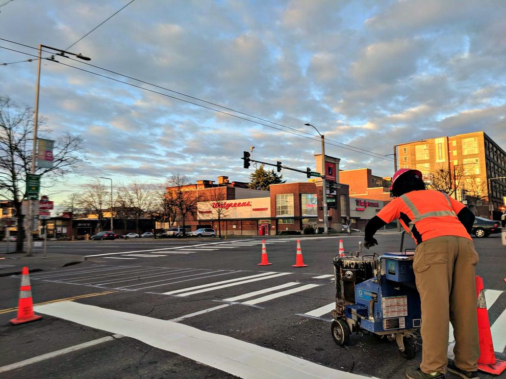 A Seattle Department of Transportation worker repairs a crosswalk at a main intersection in Ballard