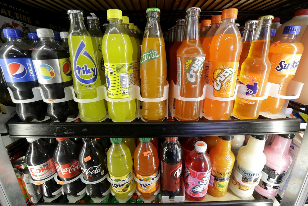 Soda bottles lined up in a store fridge