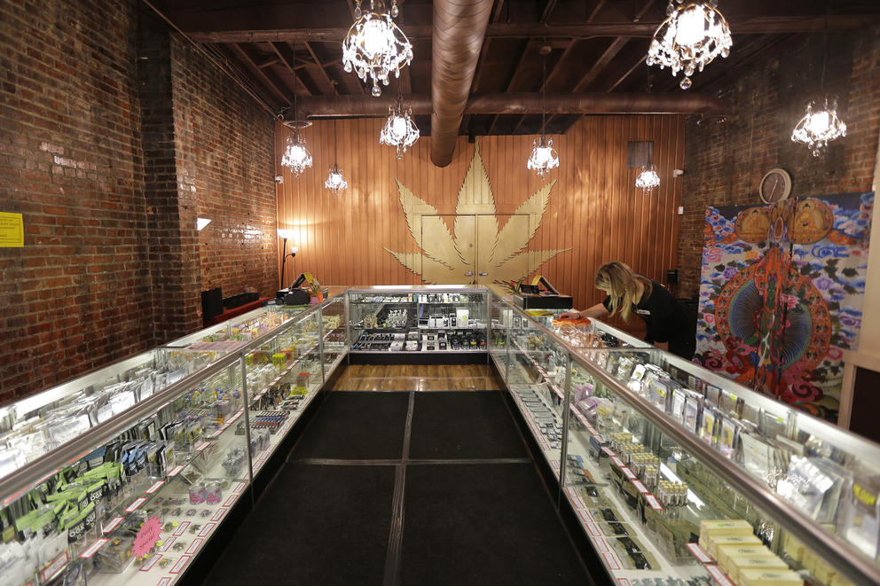 Shelves of marijuana product to left and right that recede into the distance of a store