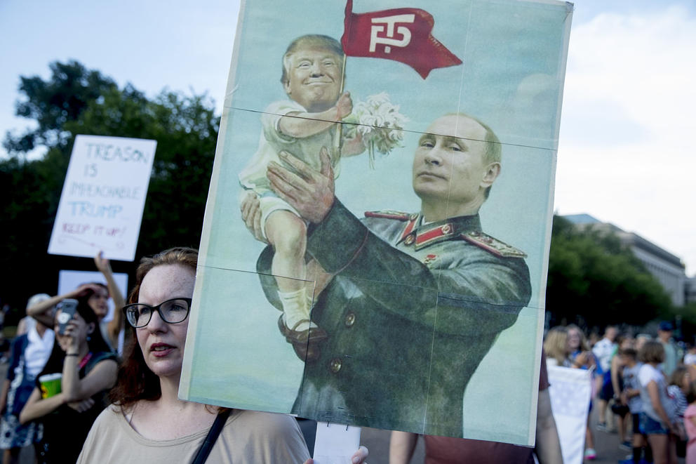 A woman holds a sign depicting Russian President Vladimir Putin and President Donald Trump during a protest outside the White House, Tuesday, July 17, 2018, in Washington. (AP Photo/Andrew Harnik)