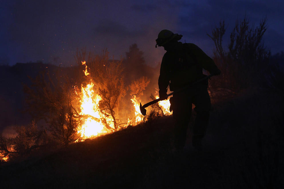 In this photo taken on Friday evening, Aug. 21, 2015, Gold Bar fire Lt. Scott Coulson investigates brush fires in the hills outside of Omak,  Wash., as wildfires continue to burn throughout north-central Washington.  (Genna Martin/The Herald via AP) 