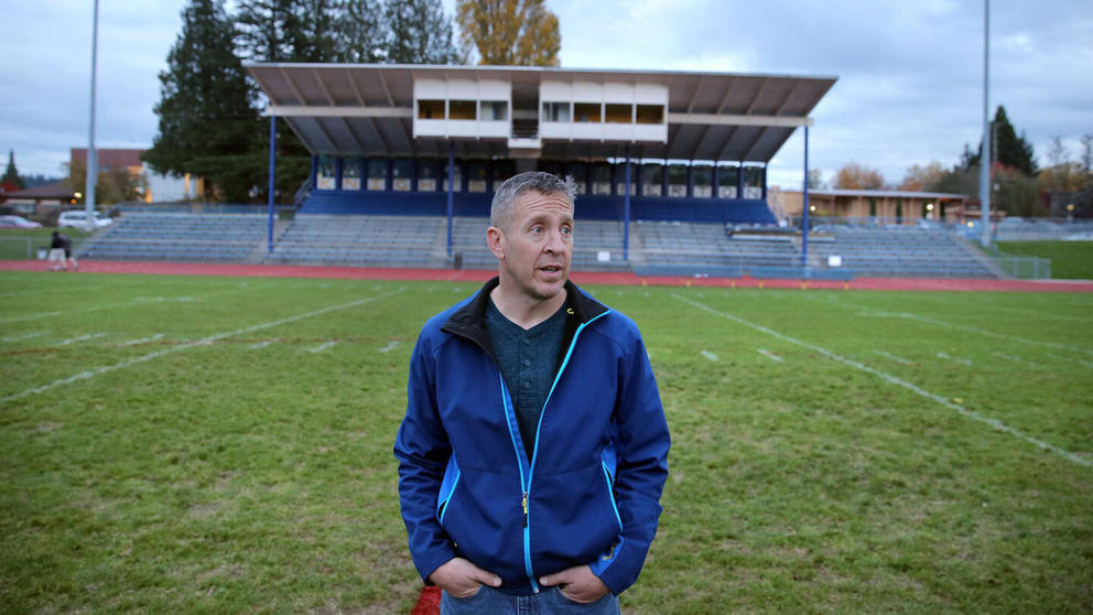 Former Bremerton High School assistant football coach Joe Kennedy stands in the middle of a football field.