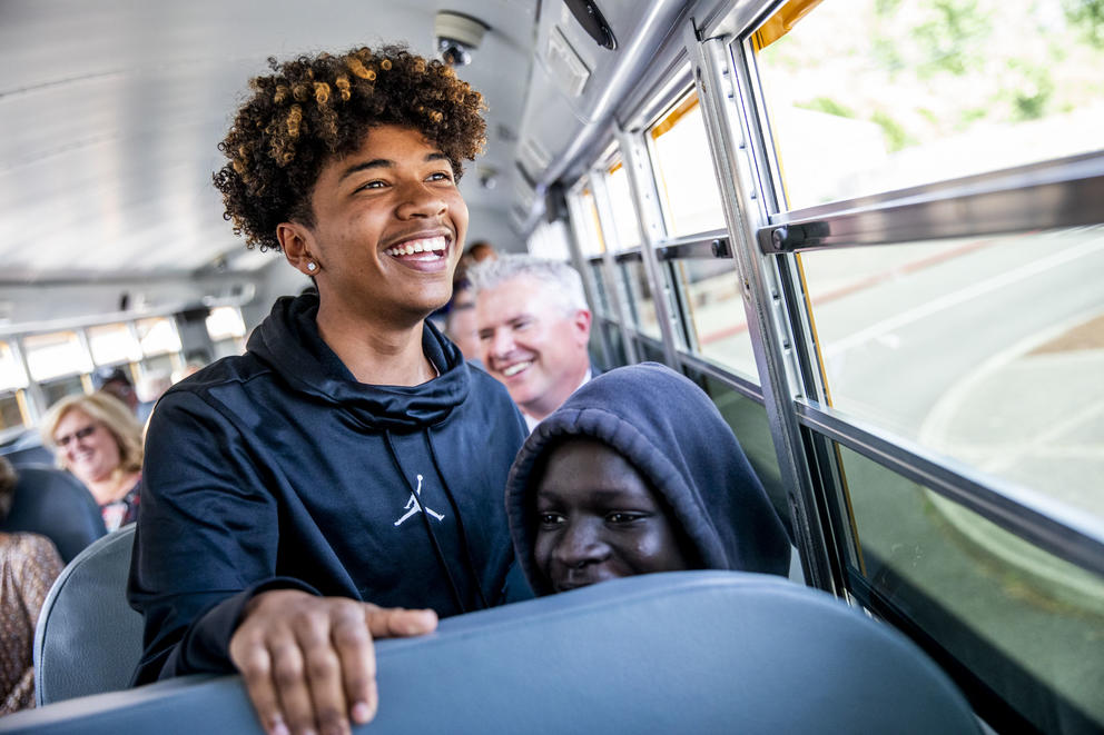 Freshmen Malik Goodrum, left, and Modi Wani ride the first electric school bus in Washington state during an event with Governor Jay Inslee at Franklin Pierce High School in Tacoma on June 17, 2019. "I feel pretty privileged to be on this bus with Governor Inslee right now," Goodrum says. (Photo by Dorothy Edwards/Crosscut)