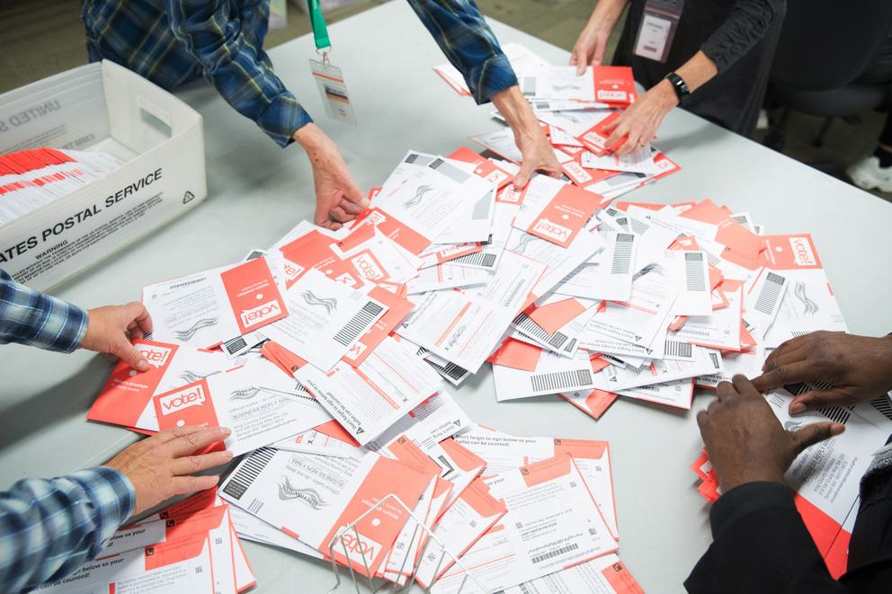 hands sorting red and white ballots on a table