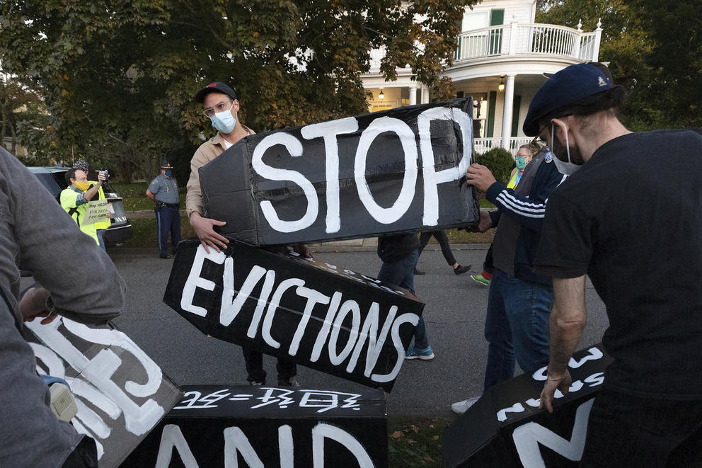 protestors hold up signs saying stop evictions