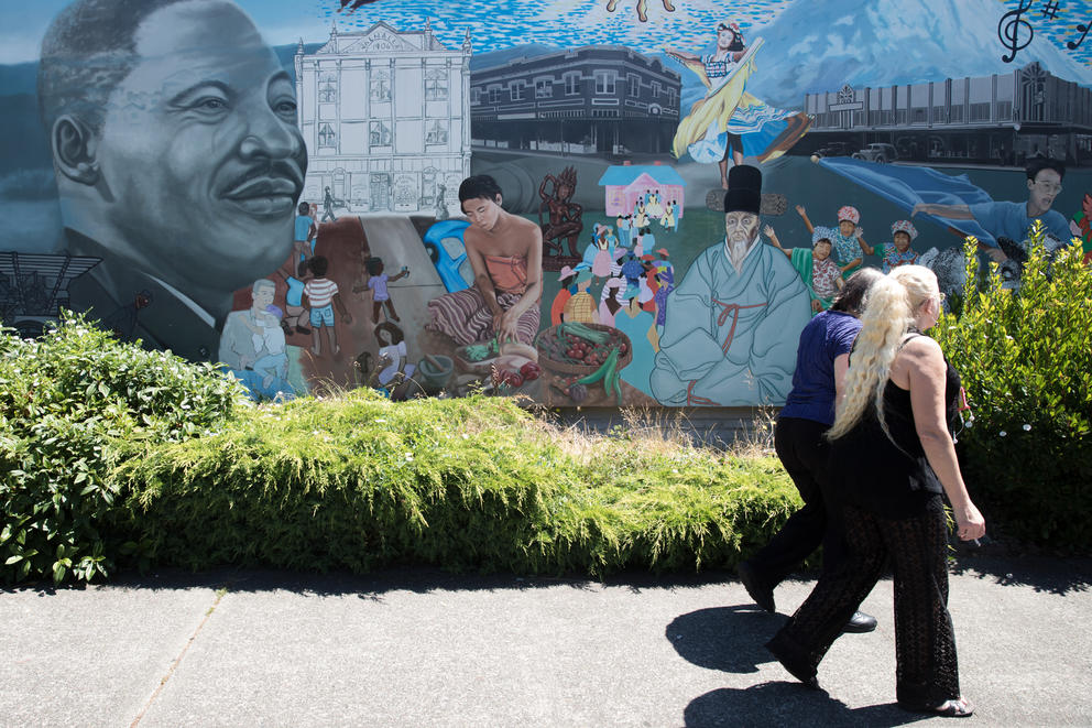 Two women walk by a mural in Tacoma's Hilltop neighborhood
