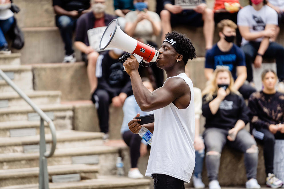A man holding a megaphone addresses a crowd