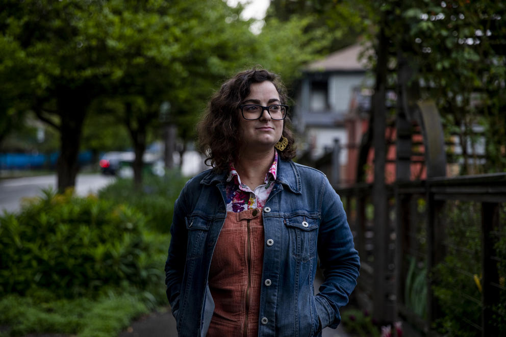 a woman in a jean jacket and glasses outdoors