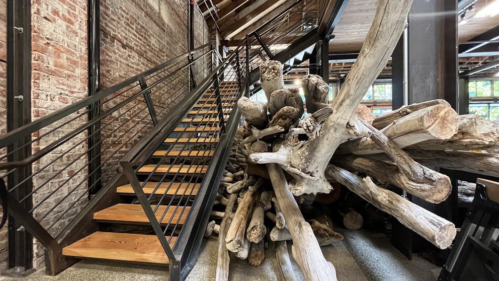 photo of a staircase next to which is a huge stack of giant driftwood