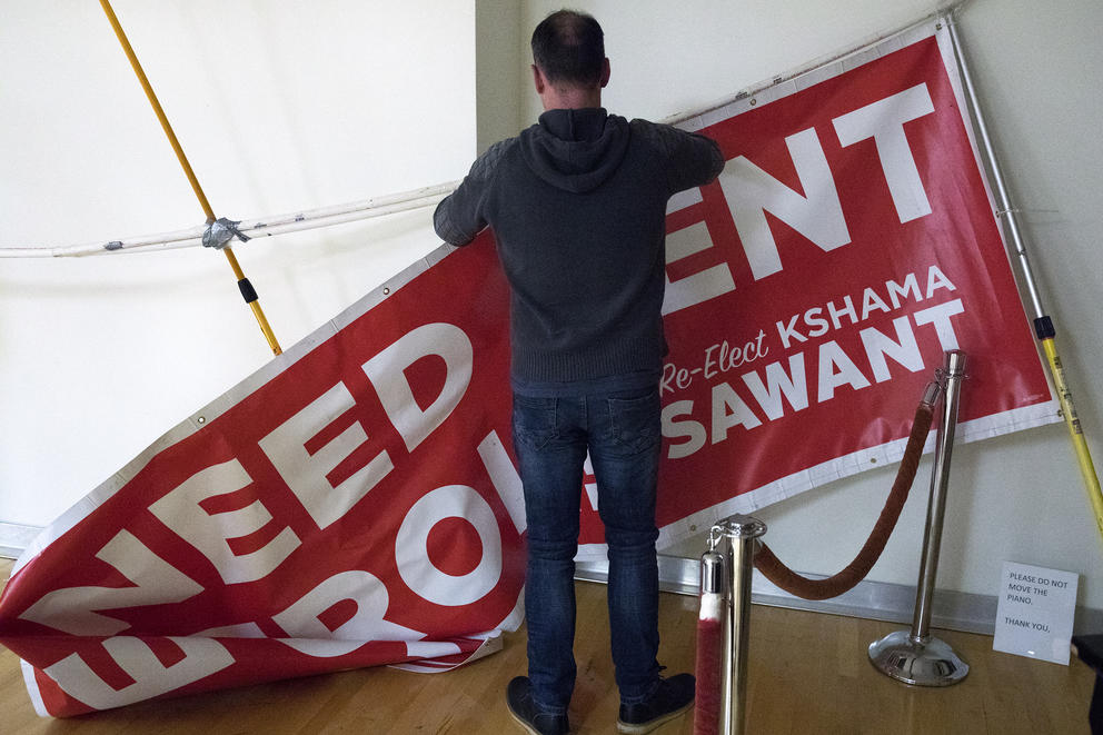 A man takes down a sign encouraging rent control