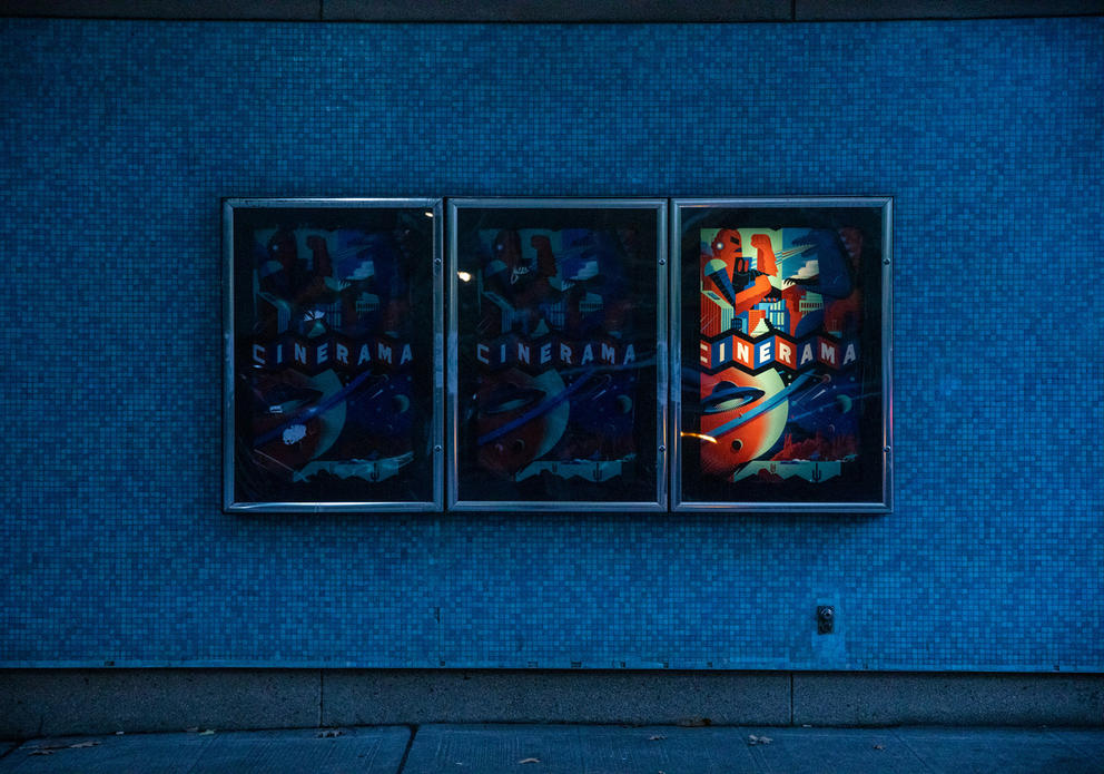 three posters hang horizontally, only the right one is lit up and says “Cinerama”