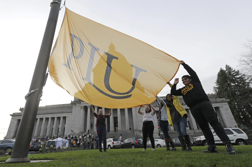 Pacific Lutheran University students raise a PLU flag.