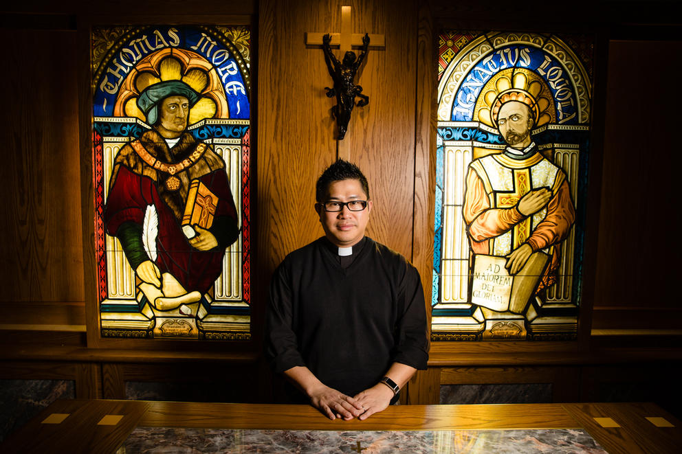 Rev. Bryan Pham stands in front of stained glass windows
