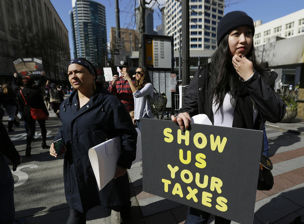 Protester holding a sign that reads "Show us your taxes"