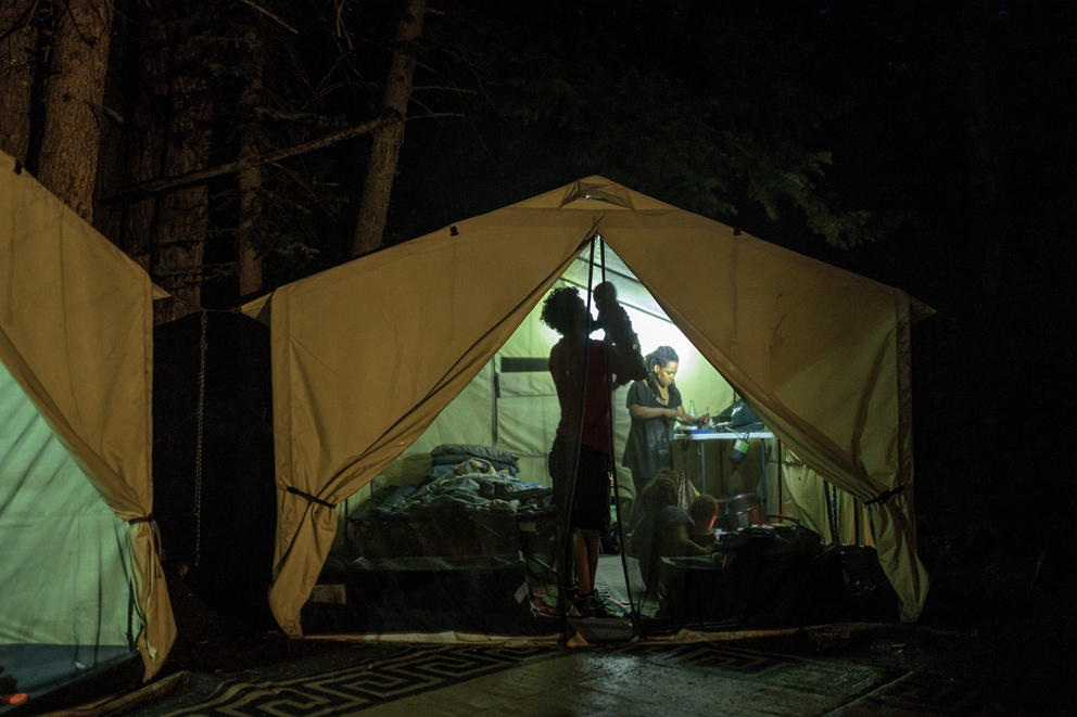 A man holds a baby aloft inside a canvas tent