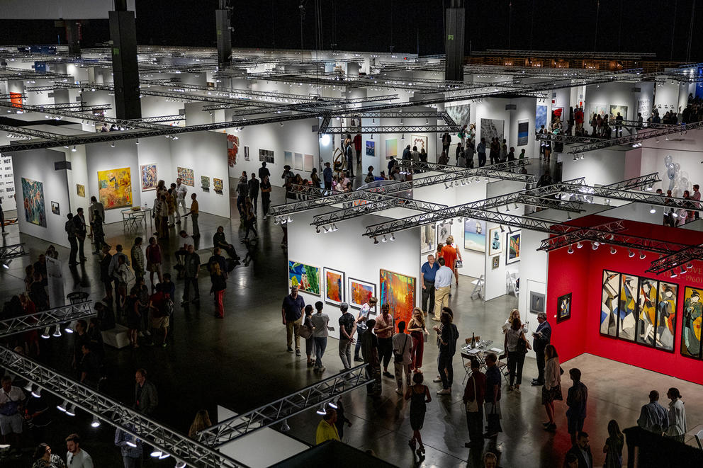 photo of an arts fair from above with many square gallery booths filled with milling people