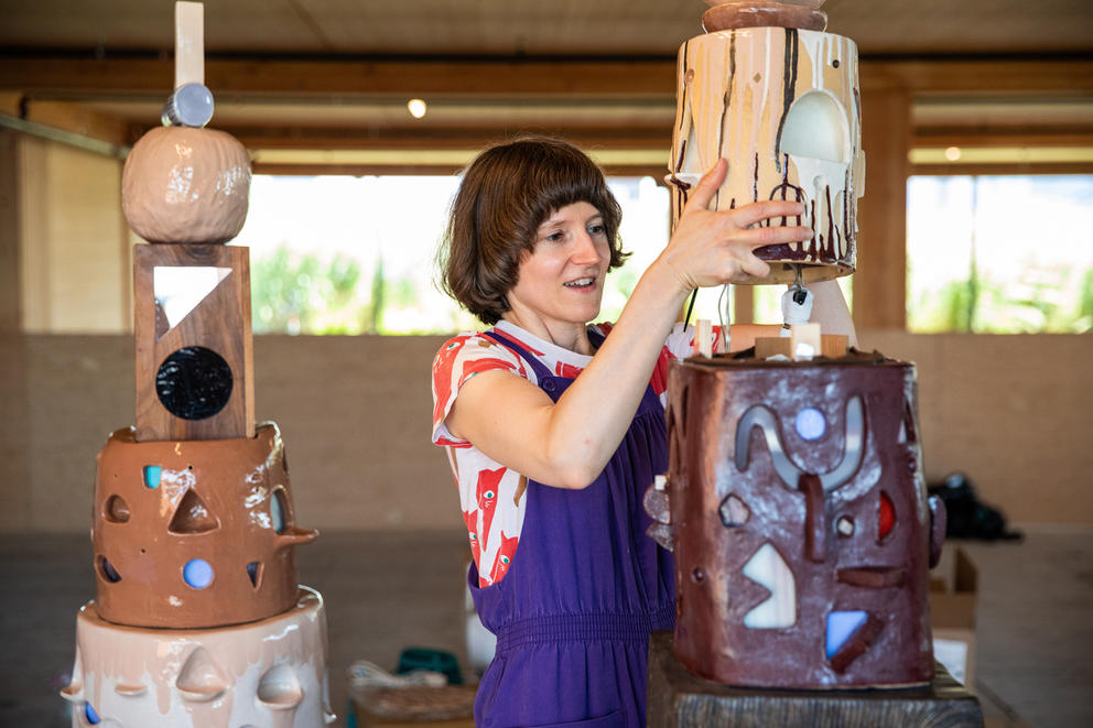 Person with brown short bob installs a ceramic head on a piece of darker-colored ceramics