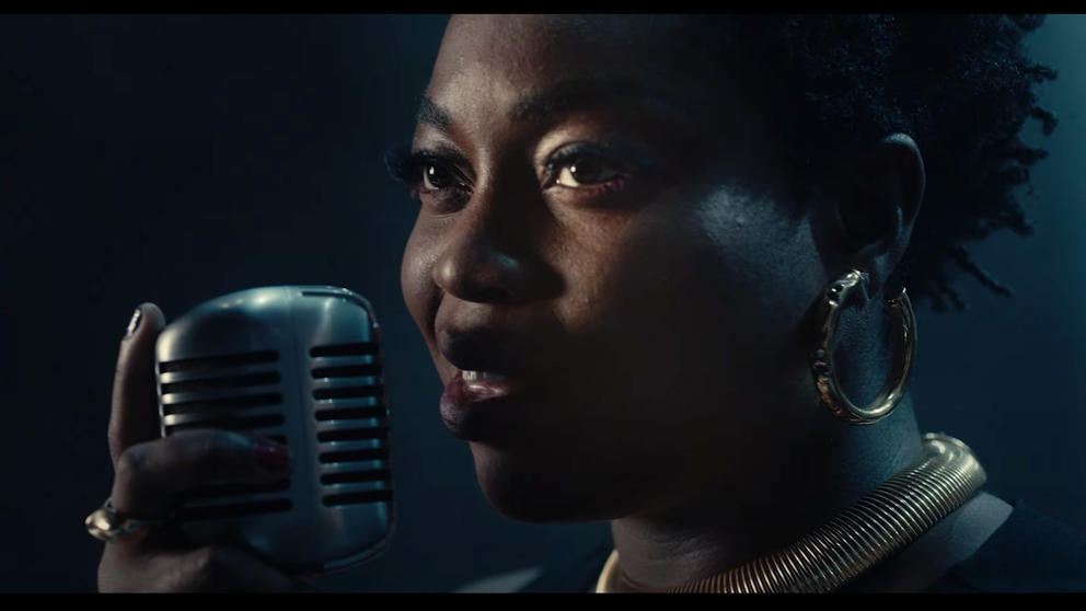 close photo of a Black woman singing at a microphone