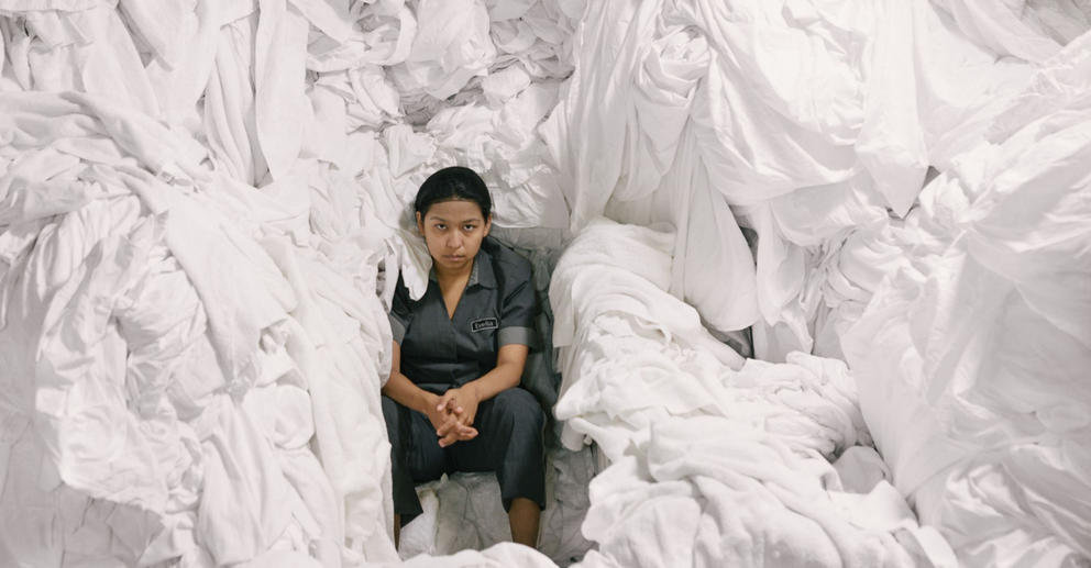 A woman sits in a pile of laundry