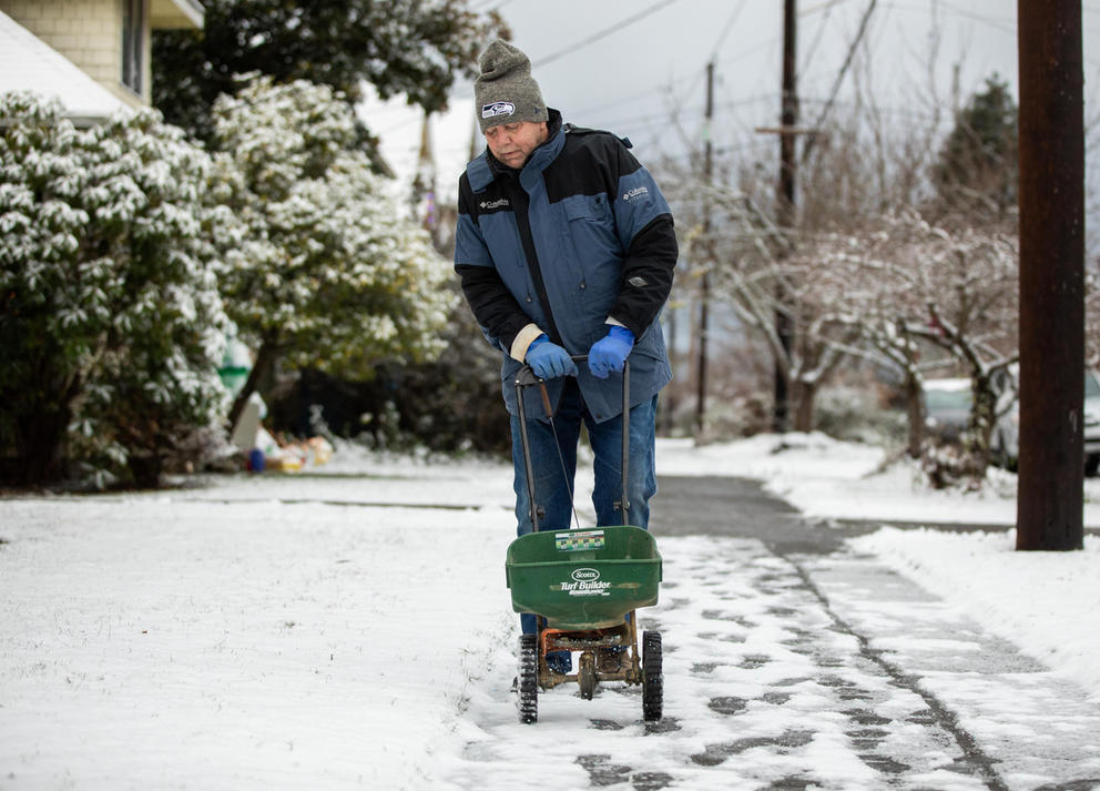 A man works on a snowy sidewalk