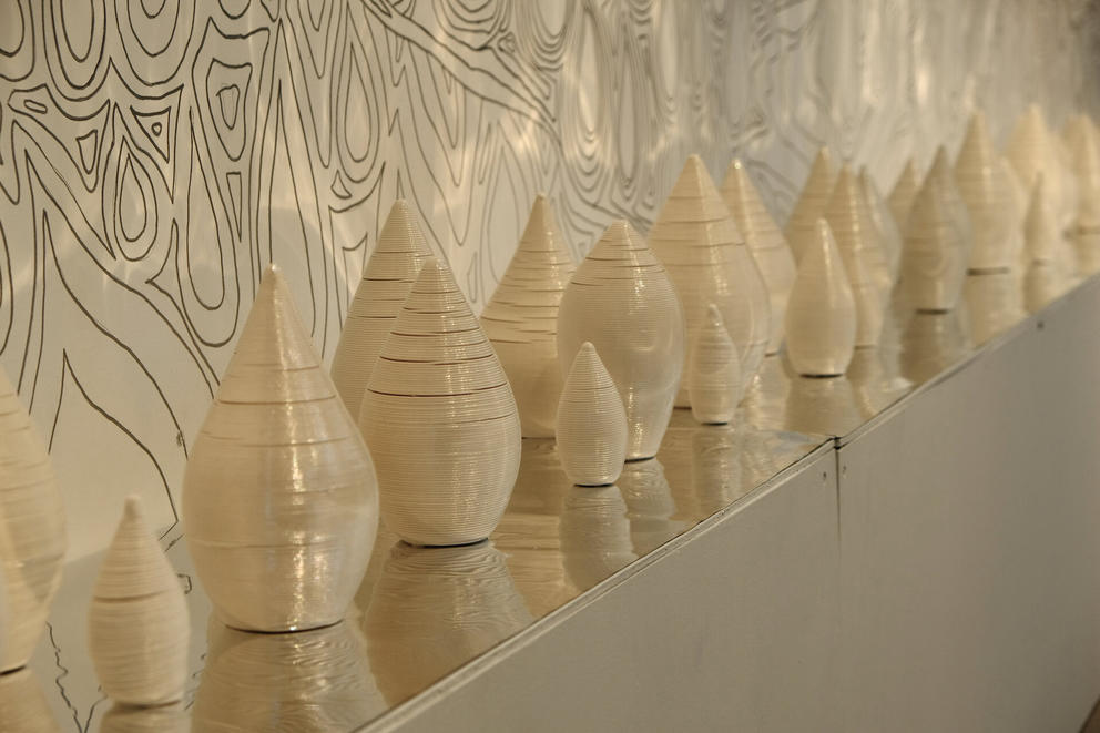 a shelf lined with raindrop shaped cream colored ceramics