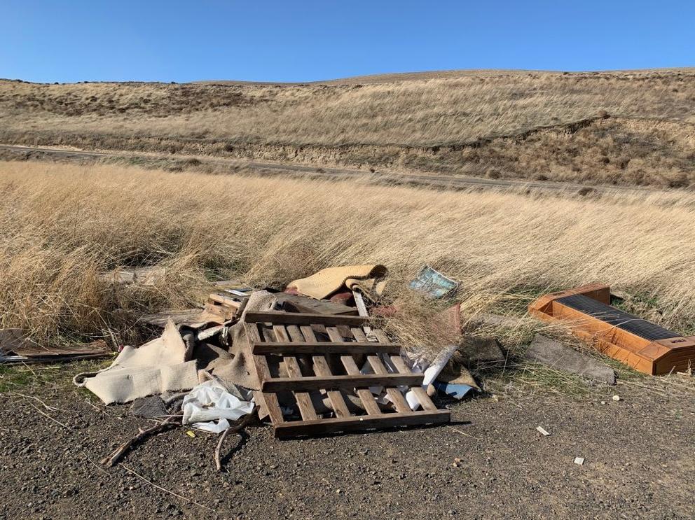 A wood pallet and other trash along a road 