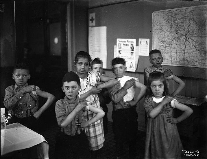 children show their arms after being vaccinated